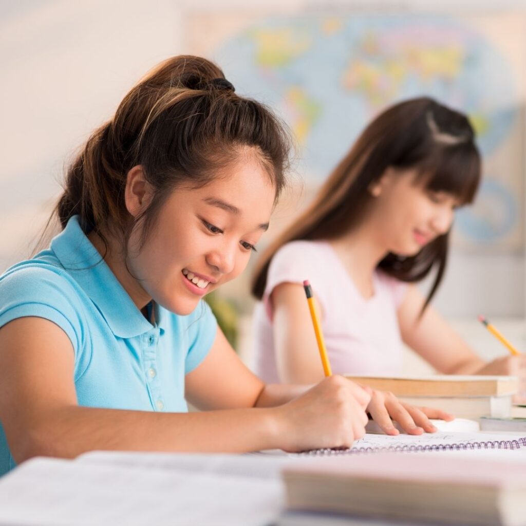 2 girls studying together writing something in their books