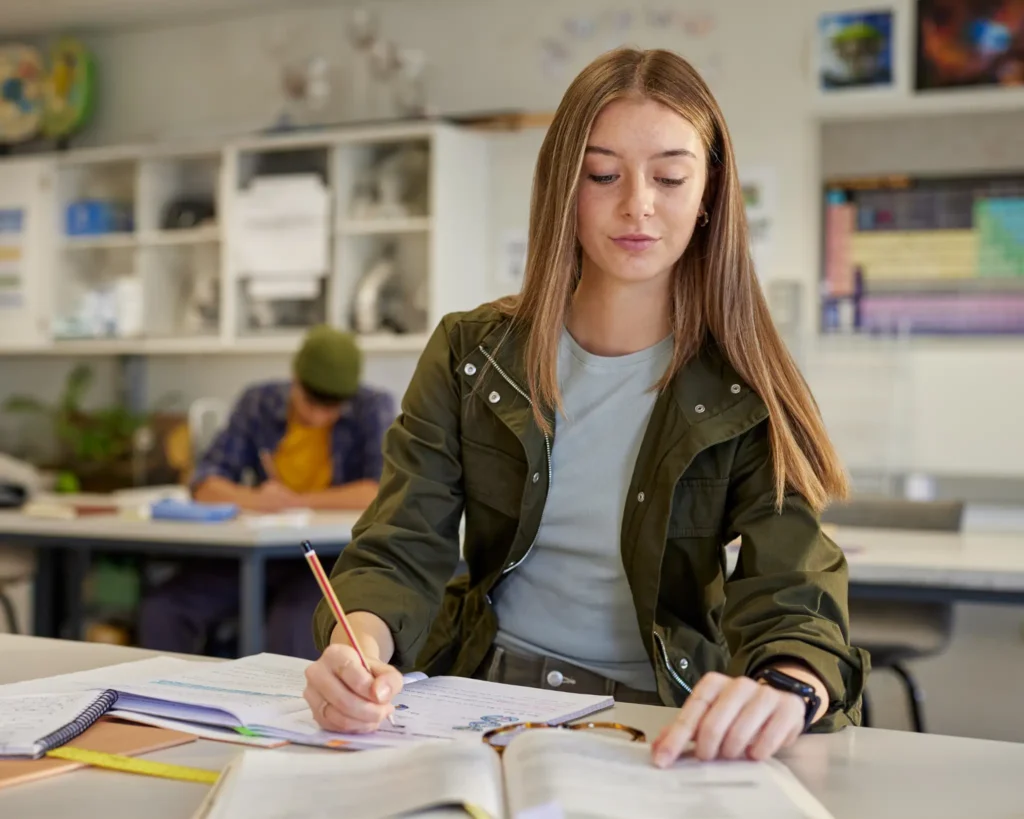 Student studying at desk with books and laptop